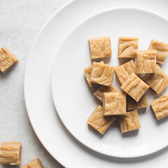 Overhead view of sliced peanut butter fudge on a white plate, top view of soft peanut fudge squares on a white ceramic plate