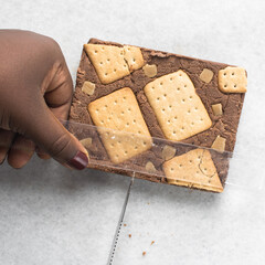 Overhead view of chocolate fudge with cookies and fudge being cut into pieces on a white tray, Top view of hazelnut chocolate fudge cut into pieces, fudge slab on a white granite countertop
