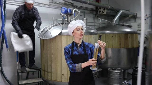 Caucasian woman brewer using alcoholometer to indicate alcoholic strength of beer.