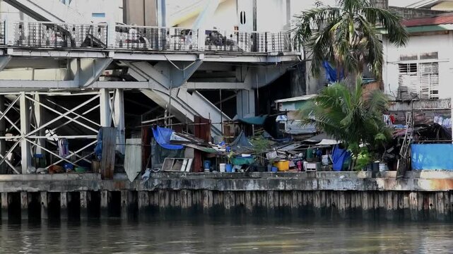 Shanty houses built under a bridge near a river in Manila
