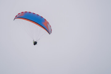 A colorful double paraglider flies in the sky