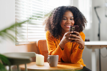Woman with afro hair, holding smartphone with coffee cup in hand stay connected online.  