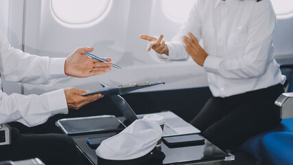 Professional pilot woman in uniform has teamwork meeting for success flight in aviation business. Young female captain instructor sitting in office and working or training commercial airline crew.