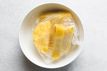 Top view of peeled chopped pineapples in a white ceramic bowl, overhead view of chopped pineapples on a white background