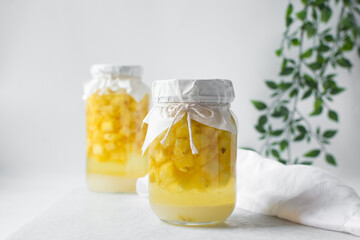 pineapple cheong in a glass jar on a white background, korean pineapple cheong in a transparent jar, pineapple in sugar syrup, process of making pineapple cheong