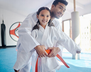 Man, sensei and girl in dojo, karate and training with teacher, skills and achievement with self defence. Orange belt, master and student in studio, success and practice with wellness and workout © Fanti/peopleimages.com