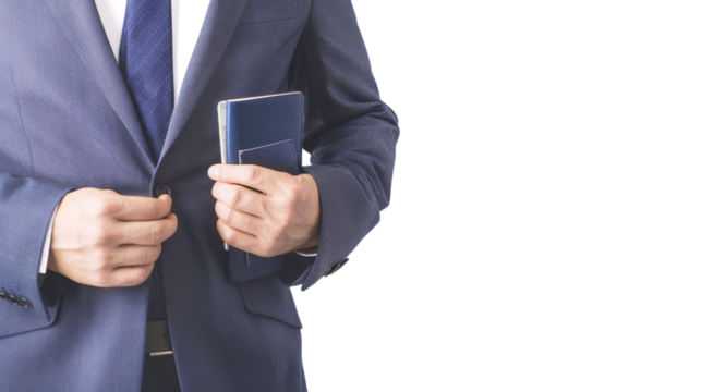 Close-up of a man in a blue suit holding a passport and buttoning his jacket