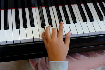 A girl's hands are pressing the piano keys, playing music.