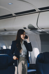 Businesswoman, confident tourist walks with suitcase, checks seat, flight number, puts her suitcase on shelf inside airplane travel lifestyle concept.