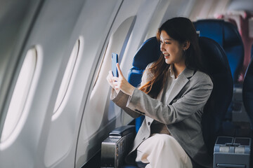 Fototapeta premium Asian woman sitting in a seat in airplane and looking out the window going on a trip vacation travel concept.Capture the allure of wanderlust with this stunning image
