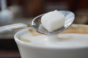 pouring white sugar cube in a coffee cup ,