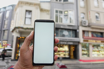 A person is holding a smartphone in an urban city environment, capturing a modern lifestyle