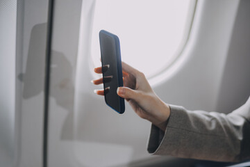 A young Asian woman, seated as an airplane passenger, contemplates dollar bills, reflecting on lucrative opportunities and aspirations towards billionaire status.