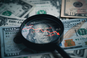 Red down arrow inside of magnifier glass and USD dollar banknote for United States of America or...