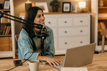 Female content creator using a laptop and mic and announcing new episode of her podcast