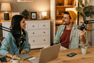 Two people in the podcast studio talking and recording during the day