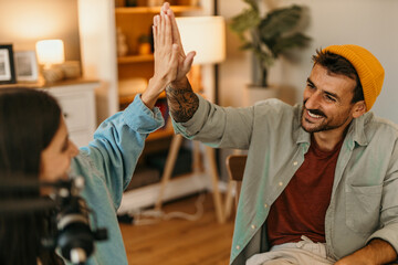 Podcasters having a hight five during a live streaming in a bright cozy studio