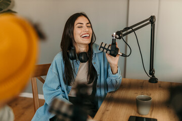 People in the podcast studio talking and recording, focus on a woman talking into a mic