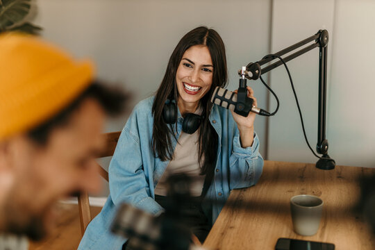 People in the podcast studio talking and recording, focus on a woman talking into a mic