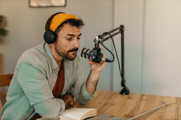 Focused man recording a podcast in a cozy living room studio, speaking into a microphone