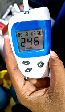 A close up of blood glucose meter with high sugar reading on wooden table