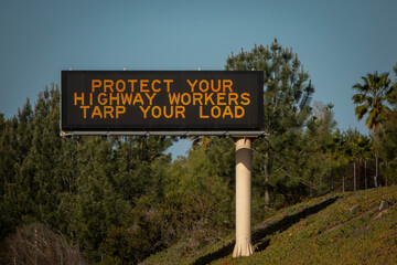 Digital freeway sign stating Protect Highway Worker Tarp Your Load