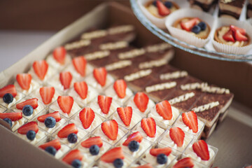 Holiday cupcakes in box, dessert decoration. toppings in a box, food preparation, catering concept. dessert food delivery in cardboard box for catering service.Tasty sweet desserts delivered for party