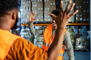 Diverse supervisor and warehouse worker greeting and preparing to clap hands. Team of experienced workers collaborating