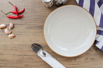 white ceramic empty plate with spoon and fork and placemat  and ingredents  on wooden background table 