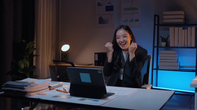 Businesswomen celebrate a successful achievement, showing teamwork and collaboration in a modern office. Join the joyful excitement around a laptop