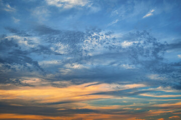Dark sky at sunset. Clouds with a bright orange stripe of sunlight on the horizon. Abstract romantic background in gentle tones.
