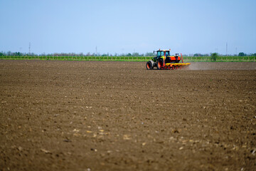 Obraz premium Agricultural land is cultivated by a tractor, sowing seeds.