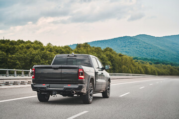 Black truck on a highway with a scenic backdrop
