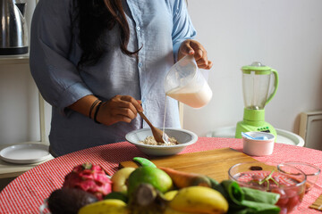 Close Up Of Hands Pouring Milk While Mixing Granola For Healthy Food Breakfast