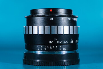 7artisans manual lens photographed on blue background, showing details of the lens' aperture number...