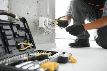 An African electrician installs electrical outlets at a construction site