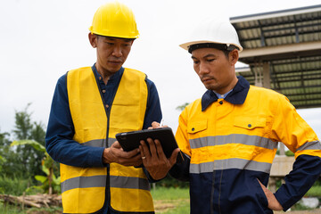 Two male architects wearing hard hats and safety vests discuss construction design on-site. collaborating with the contractor on the house structure, including iron framework, brickwork, and roofing.