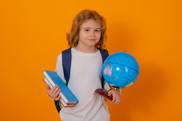 Back to school. School kid portrait. Schoolboy with world globe and book. School child student with backpack. Elementary school child. Portrait of pupil on yellow studio isolated background.