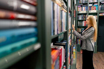 woman hand in a bookstore young girl chooses a new book for herself preparing for exams student...