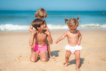 Naklejka premium Family, Games And Fun. Little Kids Enjoying, Laughing And Happy On Vacation Or Family Travel Adventures. Three Little Brothers Having Fun Playing In The Sand At The Beach.