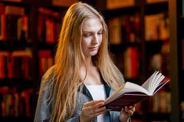 close up in a beautiful bookstore a young girl with long hair stands between the bookshelves...