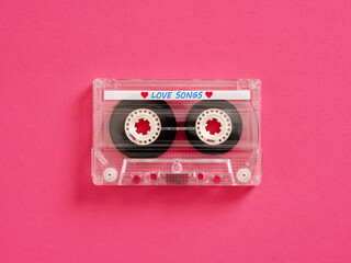 Transparent audio cassette tape lying on pink background