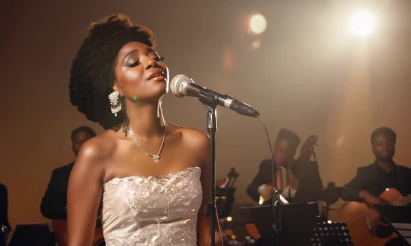 A black female jazz singer wearing an elegant gown, performing on the stage of a jazz club. Soulful voice, soft night lighting