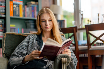 in a beautiful bookstore a young girl with long hair sitting in a chair reads a book passive rest...