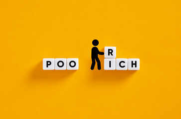 Businessman changing the word poor to rich with cubes on yellow background