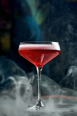An elegant pink cocktail topped with a dried orange slice, served in a stylish glass