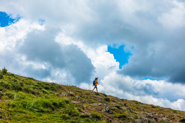 boy with a backpack walks through a mountain meadow during the summer holidays. trekking and hiking.