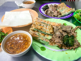 The dish includes grilled beef, grilled pork wrapped in betel leaves, and spring rolls, which will be rolled in rice paper and dipped in sauce.