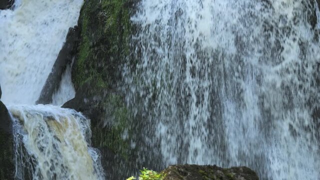 The highest waterfall of the Black Forest in Triberg, Germany. Slow motion of falling clear mountain water in detail. Big rocky stones covered with green moss in a mountain place
