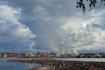 Industrial landscape with lake, stormy sky and factory during golden hour. Industry harmonized with nature concept